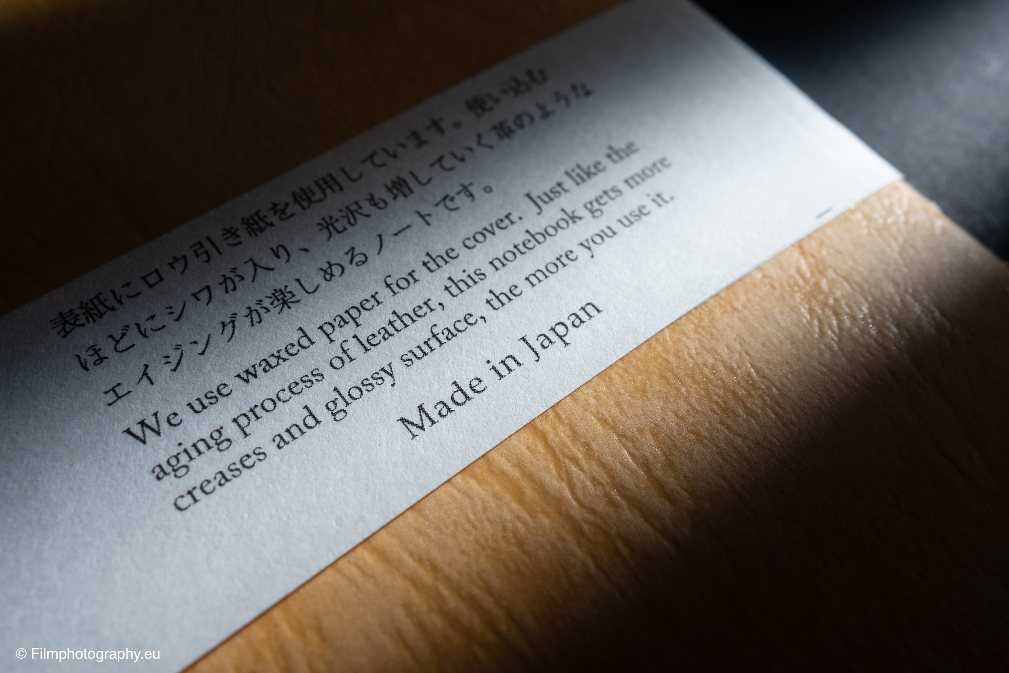 Nahaufnahme von Yamamoto Robiki Notizpapier-Einlage auf Holzoberfläche, zweisprachiger Text, warme Filmtöne mit geringer Schärfentiefe