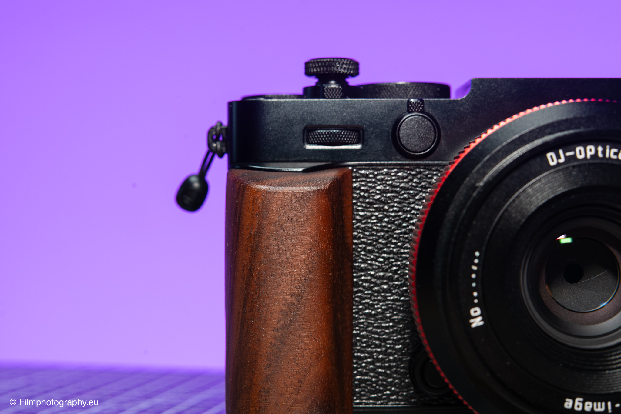 Fujifilm X-E5相机特写，木制手柄与DJ-Optics镜头，紫色背景