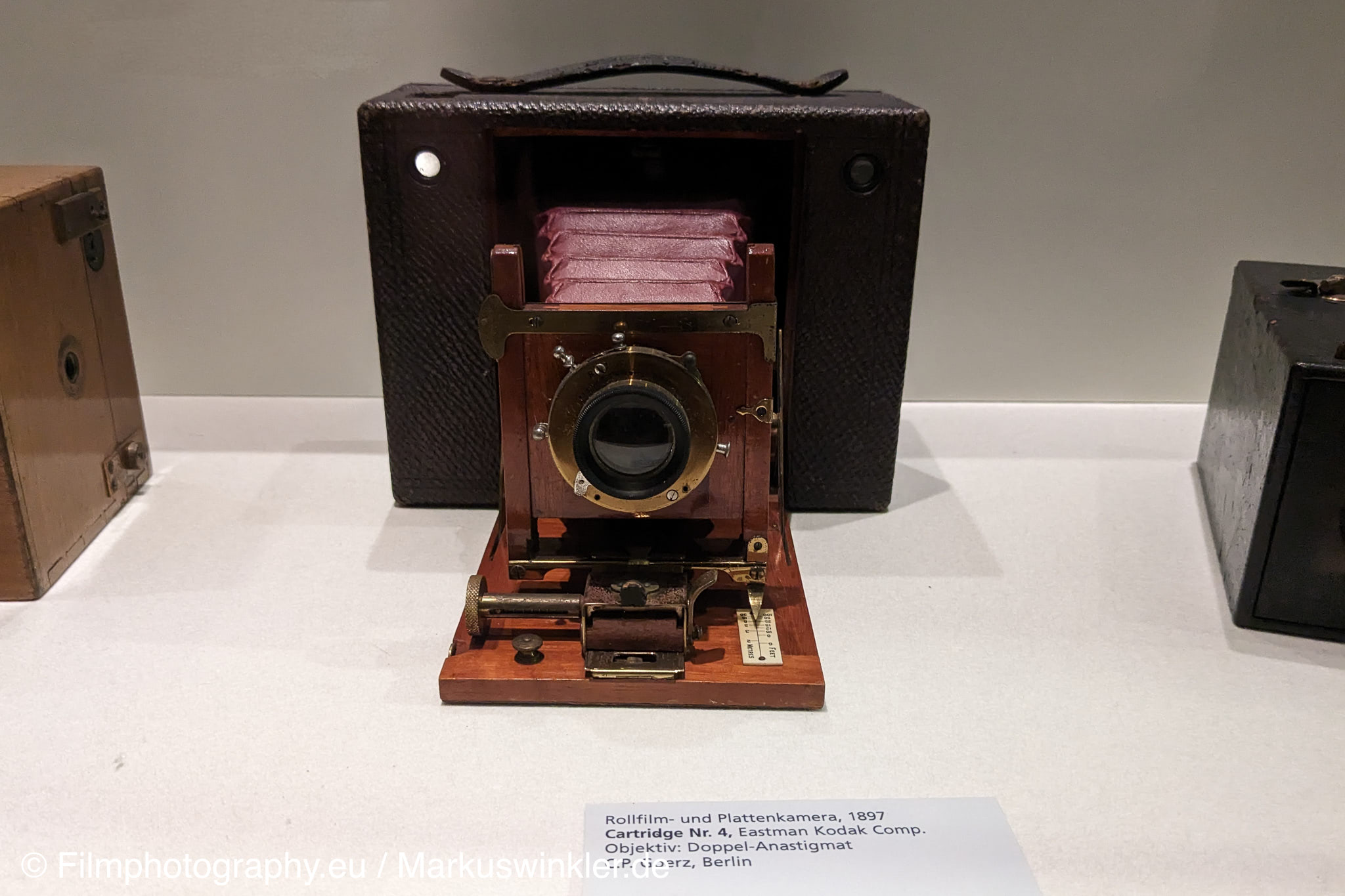 1897 का प्राचीन Eastman Kodak Cartridge No. 4 प्लेट कैमरा, पीतल का लेंस और लाल बेलोज़, संग्रहालय में प्रदर्शित।